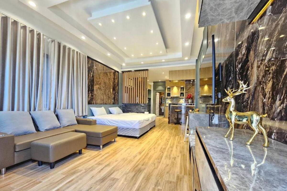 Ein modernes Wohnzimmer mit Ecksofa, einem Bett, einer Küchenzeile und einer Marmorplatte mit einer goldenen Hirschskulptur.