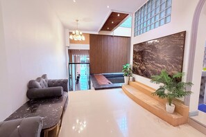 A spacious living area with a modern sofa, a dining table, a large abstract painting, and a potted plant. - M&M Rooftop Pattaya (Pattaya)