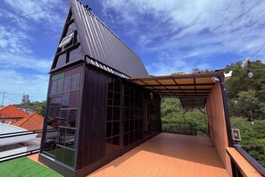 A modern building with a sloped roof, large windows, and a wooden deck. - M&M Rooftop Pattaya (Pattaya)