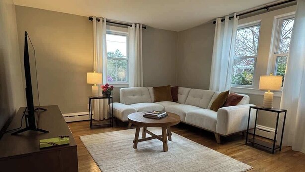 Un salon avec un canapé, une table basse, un téléviseur et des lampes.