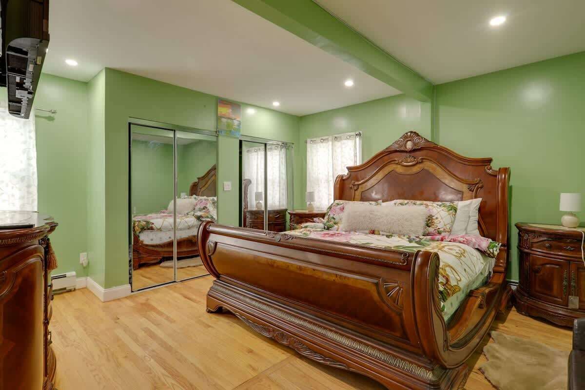 A bedroom with a large bed, a mirror, and a wardrobe.