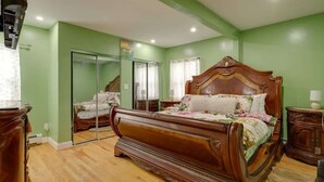 Een slaapkamer met een groot bed, een spiegel en een kledingkast.