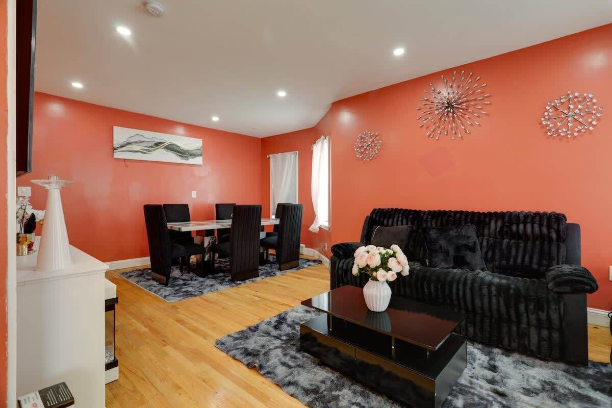 A living room with a black sofa, a coffee table, and a dining area with chairs and a table.