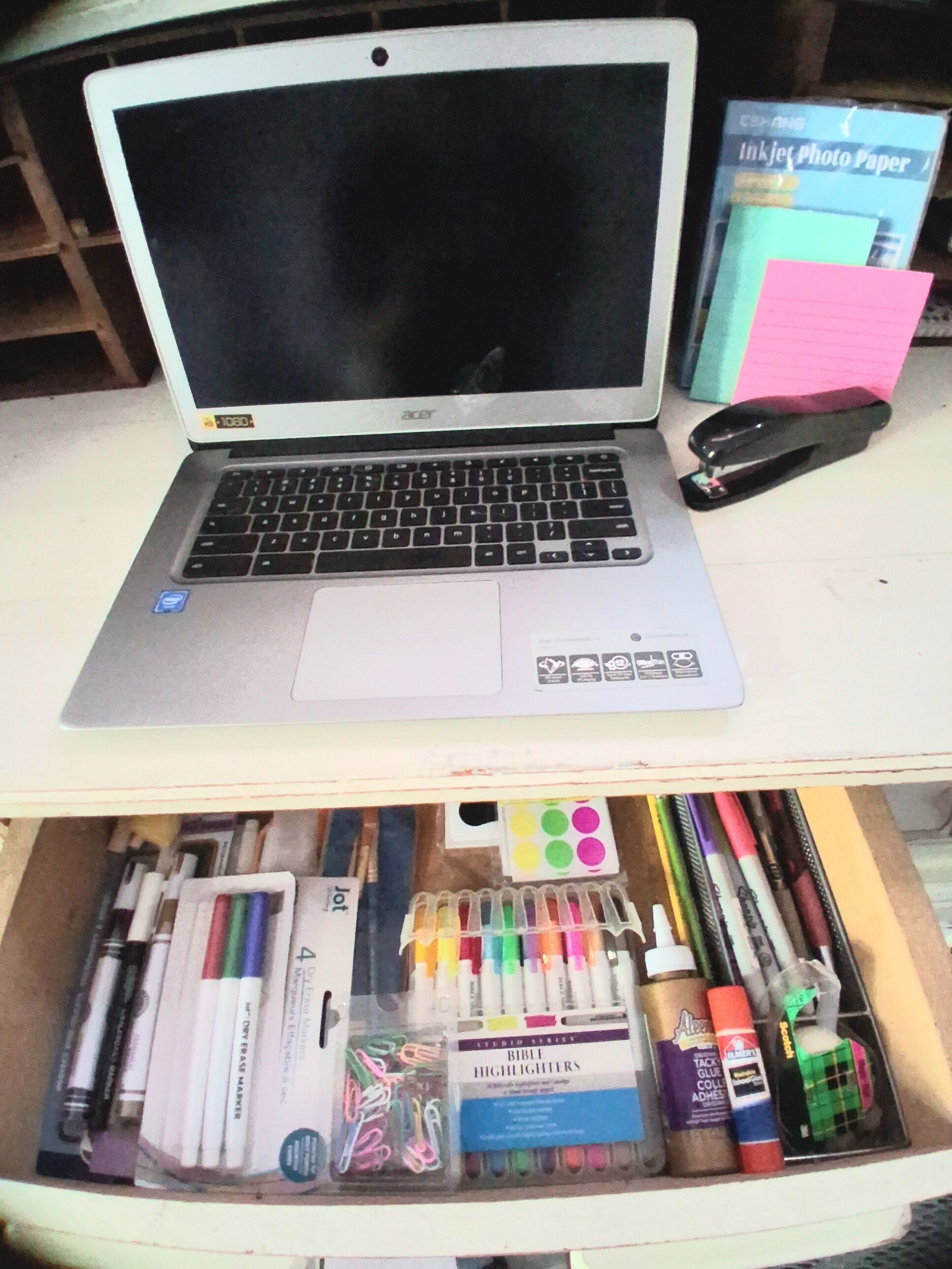 Ein Laptop auf einem Schreibtisch zusammen mit verschiedenen Schreibutensilien wie Markern, Textmarkern und einem Hefter.