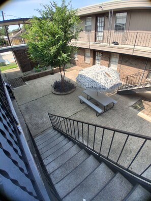 A courtyard with a staircase, a picnic table, and a tree.