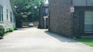 Una calle residencial con un coche estacionado, un edificio de ladrillo y un letrero que indica propiedad privada, prohibido estacionar.