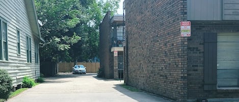 A residential street with a parked car, a brick building, and a sign indicating private property with no parking.
