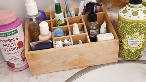 Un baño con un organizador de madera que contiene varios artículos de aseo.
