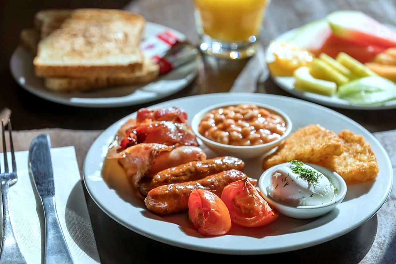 A plate with sausages, tomatoes, beans, and toast.