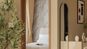 Moderni hotellihuone, jossa on sänky, peili, ruukkukasvi ja tuoli.