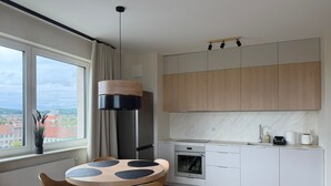 Une cuisine moderne avec un coin repas, de grandes fenêtres et une vue sur la ville.