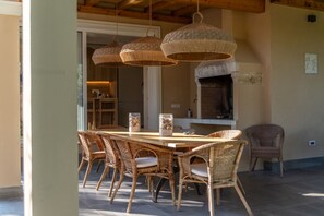 A dining area with wicker chairs, a wooden table, and hanging wicker lamps. - Design Villa La Vela - Goelba (Capoliveri)