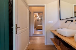 A hallway leading to a bedroom with a bed, a bathroom with a sink, and a mirror. - Design Villa La Vela - Goelba (Capoliveri)