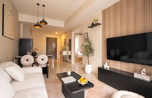 Ein modernes Wohnzimmer mit einer Couch, einem Couchtisch, einem Flachbildfernseher und einem Essbereich mit Stühlen und einem Tisch.