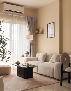 Ein modernes Wohnzimmer mit einer Couch, einem Couchtisch, einem Sessel, einem Topf mit Pflanze und einem gerahmten Bild an der Wand.