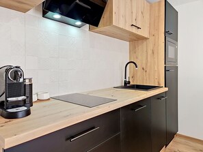 Eine moderne Küche mit Holzarbeitsplatte, schwarzen Schränken, einem schwarzen Wasserhahn und einem eingebauten Backofen.