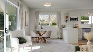 Een moderne keuken met een magnetron, een eethoek met een tafel en stoelen, en een groot raam met gordijnen.