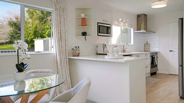 Een moderne keuken met een glazen eettafel, witte kastjes en uitzicht op de omgeving.
