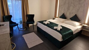 Habitación de hotel con cama, dos sillas, una mesita y vistas al exterior.
