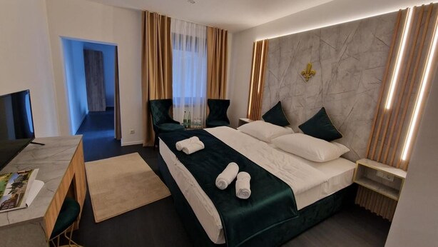 Habitación de hotel moderna con una cama grande, un escritorio con una computadora y vistas al exterior.