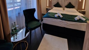 Habitación de hotel con cama, una silla, una mesita con vasos y vistas a través de la ventana.