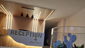 Un mostrador de recepción con un cartel que dice 'RECEPTION Lilum Resort' y un jarrón de vidrio con una decoración de cactus.