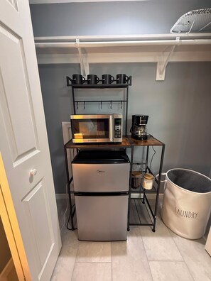 A compact kitchenette with a microwave, coffee maker, and a mini-fridge.