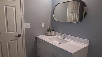 A bathroom with a white vanity, a large mirror, and a lighted vanity mirror.