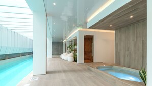 A modern indoor swimming pool area with a clear view of the pool, a wooden wall, and a seating area with white chairs. - Edificio SEIS by Host Ecuador (Quito)