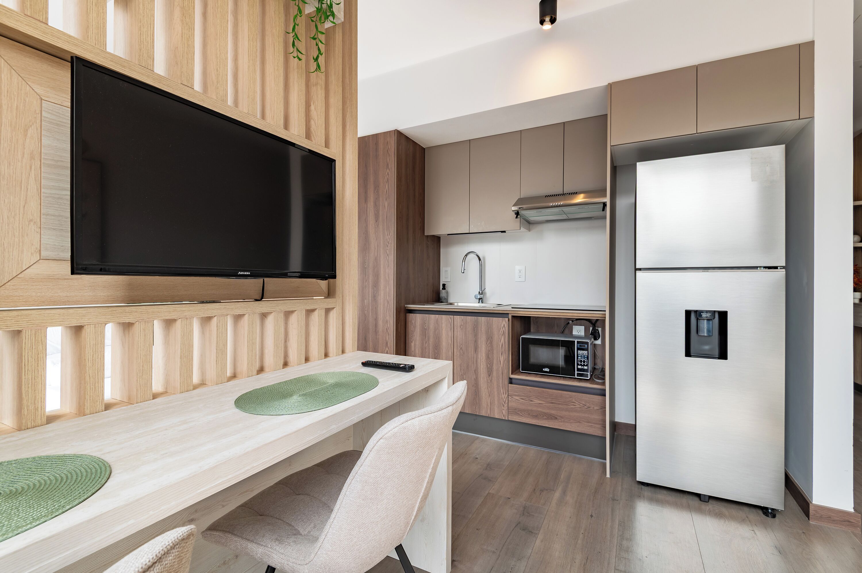 Een moderne keuken met een flatscreen televisie, een koelkast en een magnetron.