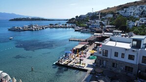 A coastal town with a marina, clear waters, and buildings with balconies overlooking the sea. - Moonlight Pansiyon (Akyarlar)