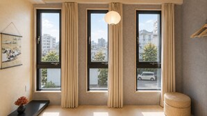 A modern room with large windows, a hanging light fixture, a black console table, and a woven ottoman. - BACOWA AWAZA (Nishi-ku, Osaka)