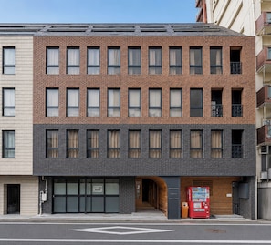 A multi-story building with a brick facade, large windows, and a ground-level entrance with a vending machine. - BACOWA AWAZA (Nishi-ku, Osaka)