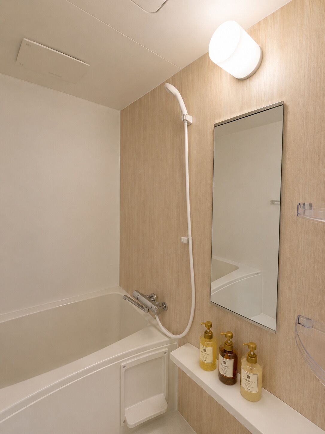 A modern bathroom with a bathtub, a shower, a mirror, and a shelf with toiletries.