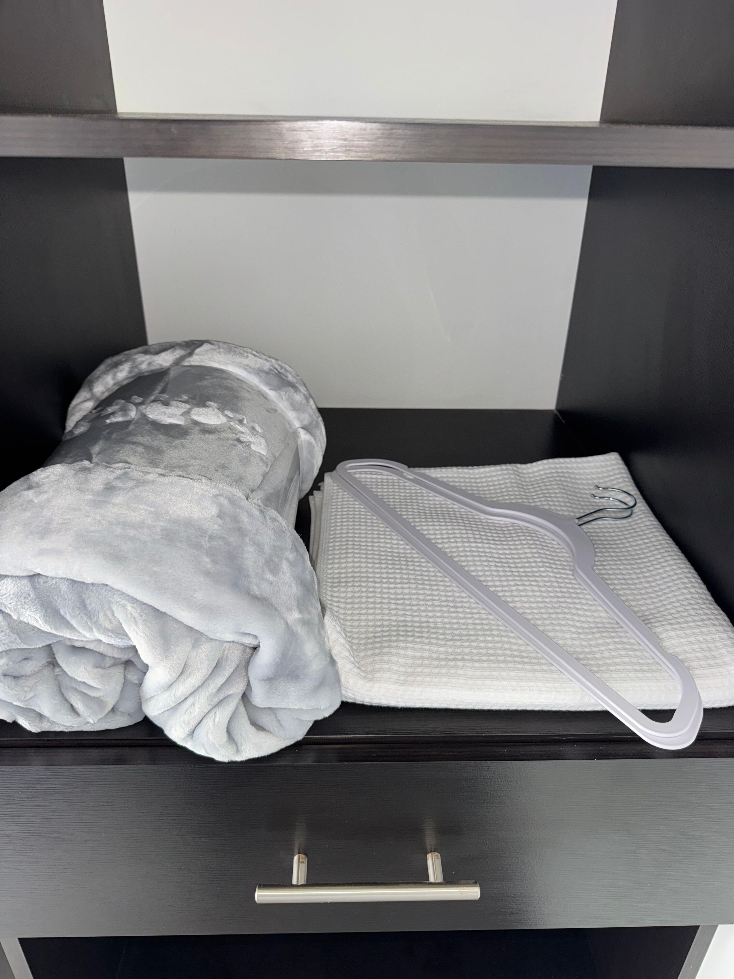 Una cama con una manta blanca y un almohadón blanco con textura.