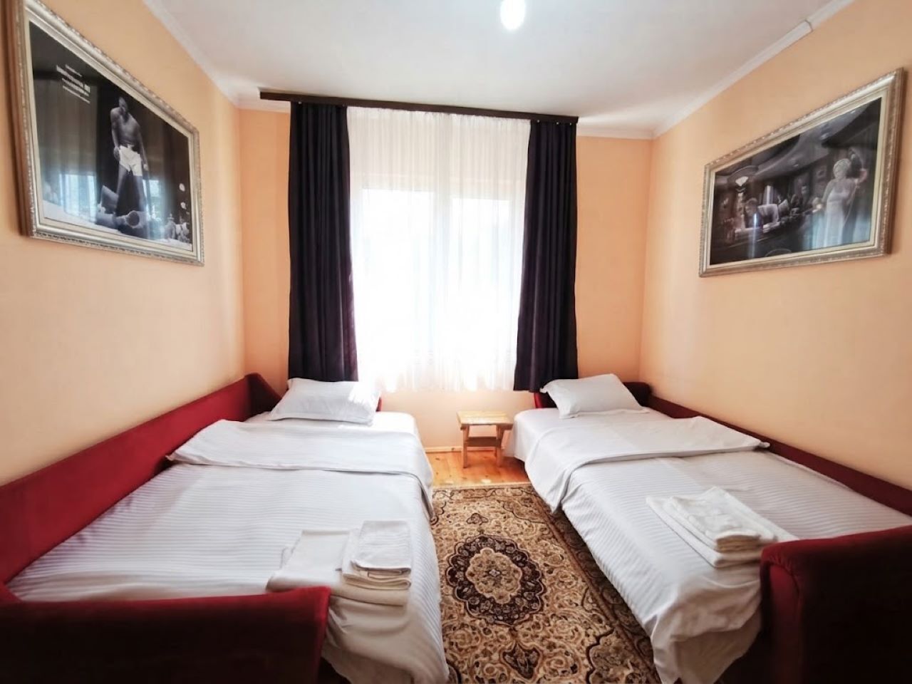 Een hotelkamer met twee bedden, een kleine tafel en een raam met gordijnen.