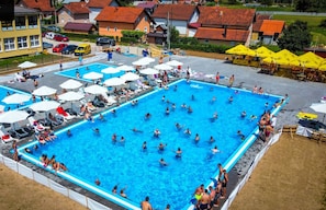 Una amplia piscina al aire libre rodeada de sombrillas y sillas de descanso.