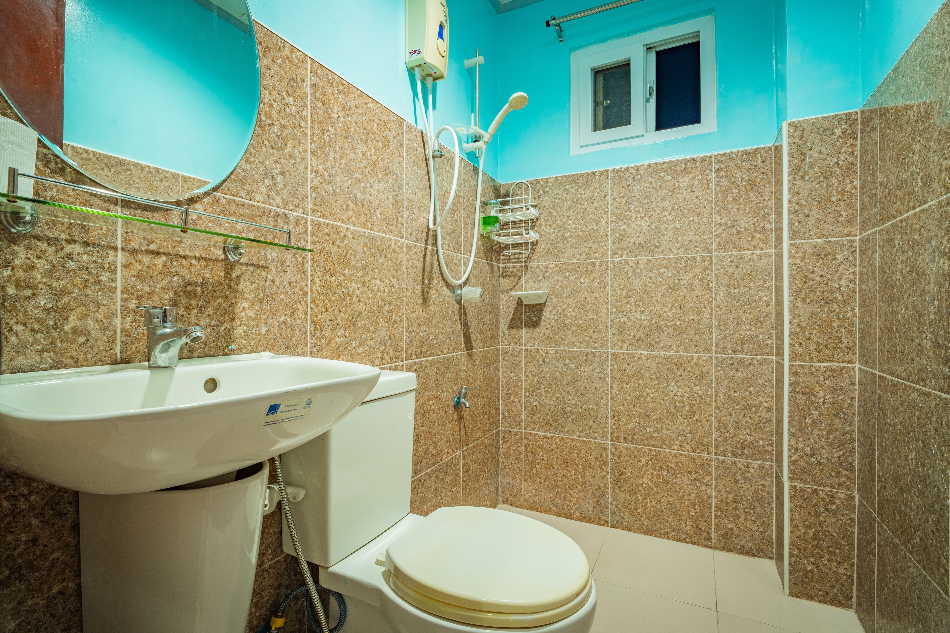 A bathroom with a sink, toilet, shower, and a small window.