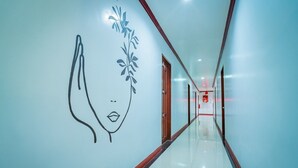 Un pasillo con un mural en la pared, puertas de vidrio y un letrero rojo de salida de emergencia.
