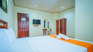 Una habitación de hotel con cama, escritorio, silla, televisor y armario.