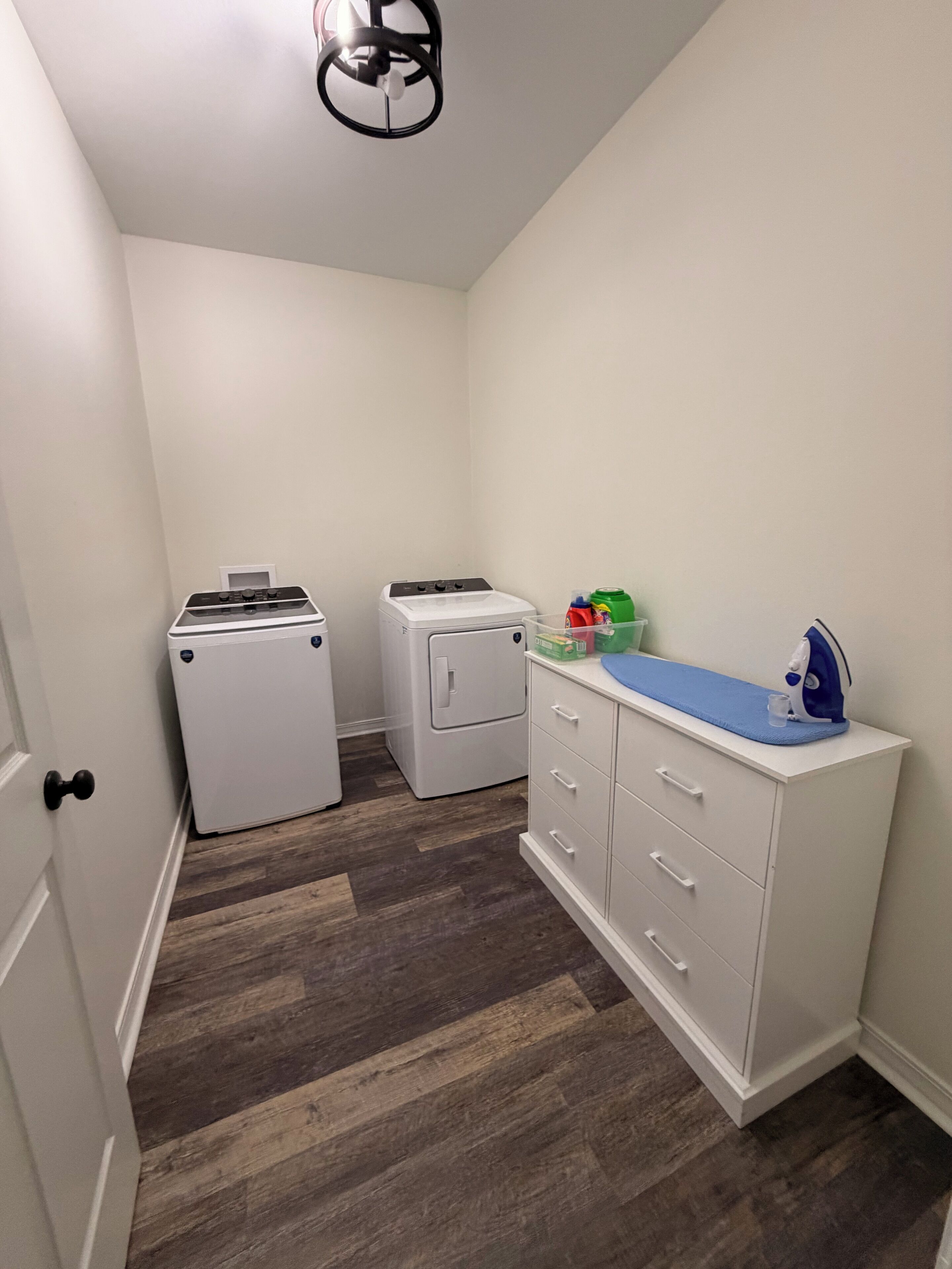 A laundry room with a washer, dryer, and ironing station.