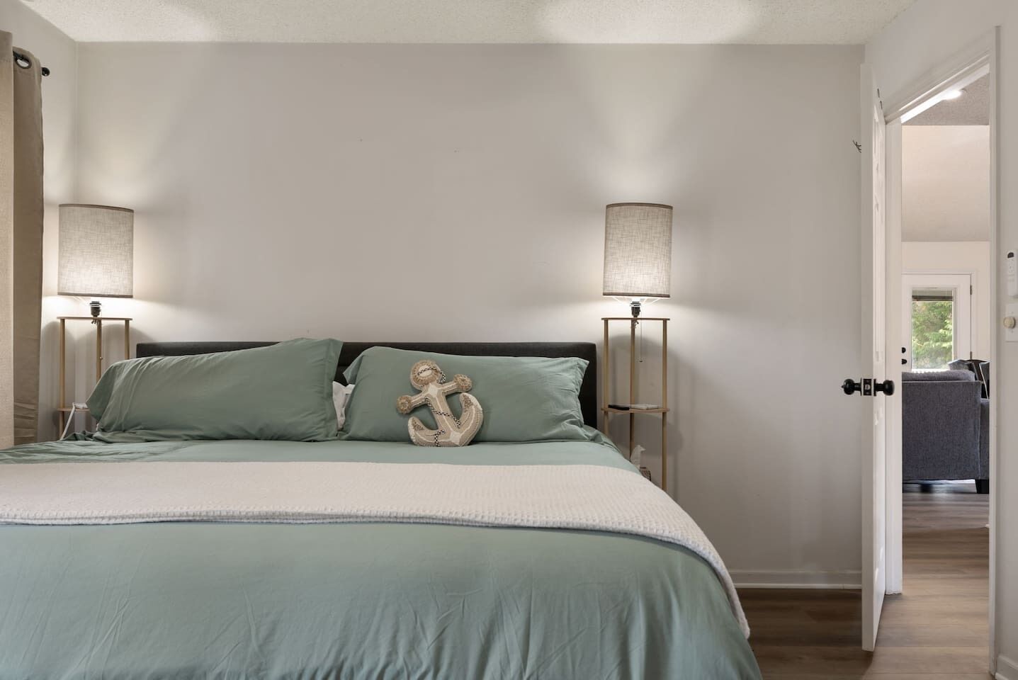 Une chambre à coucher avec un lit, deux lampes de chevet et un coussin décoratif en forme d’ancre.
