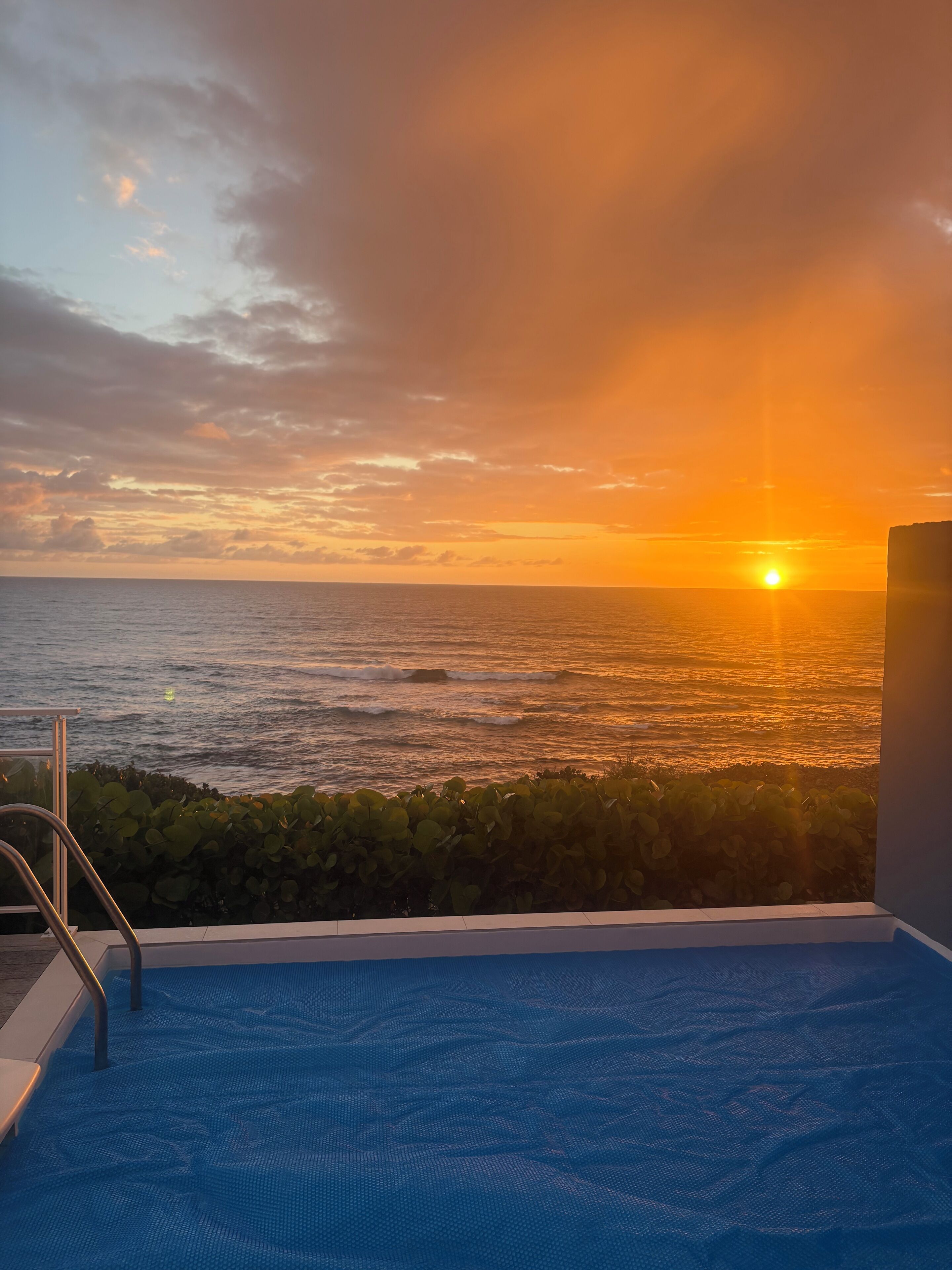Ein Poolbereich mit Blick auf den Ozean bei Sonnenuntergang.