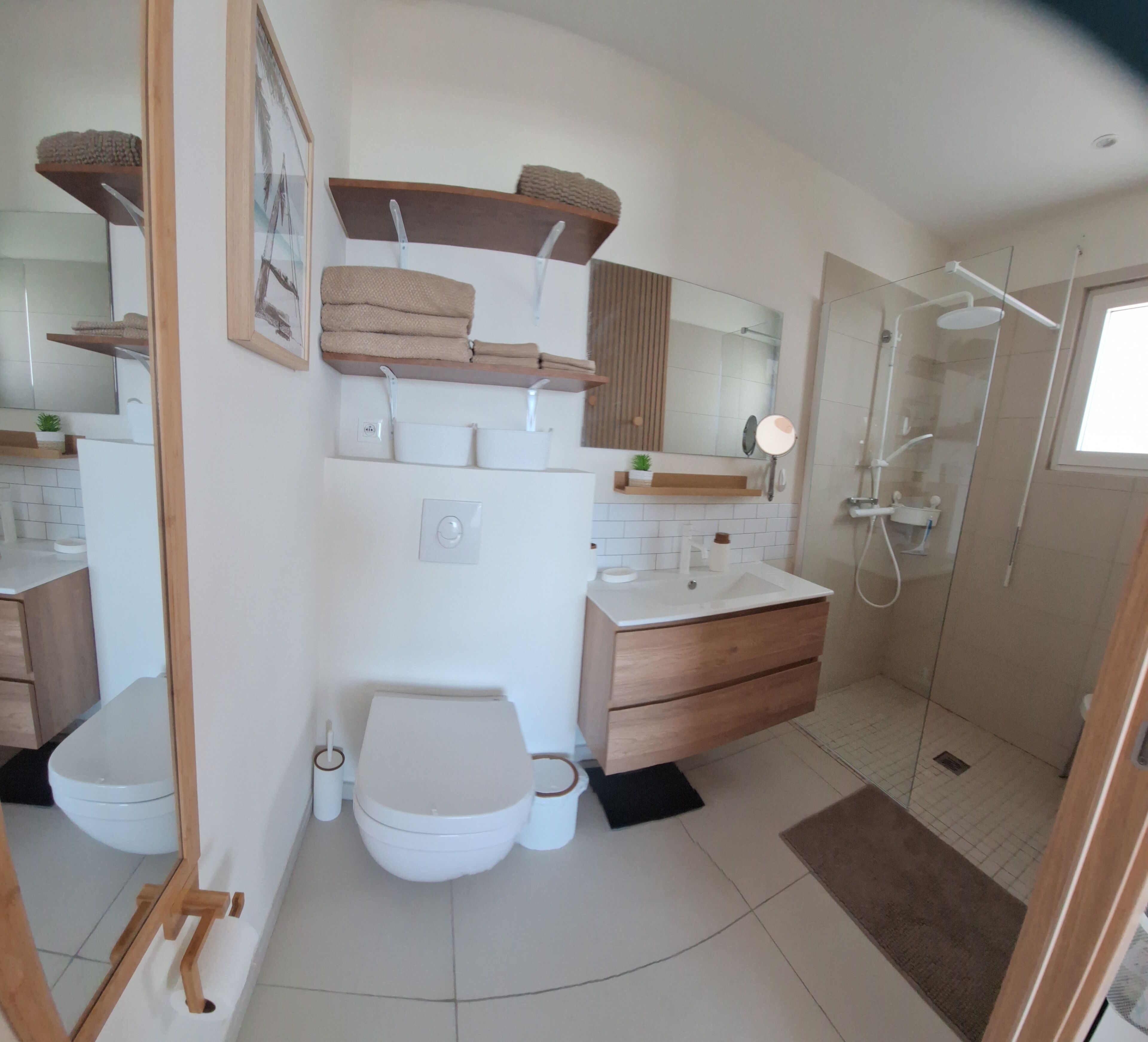 A modern bathroom with a toilet, sink, mirror, and shower.
