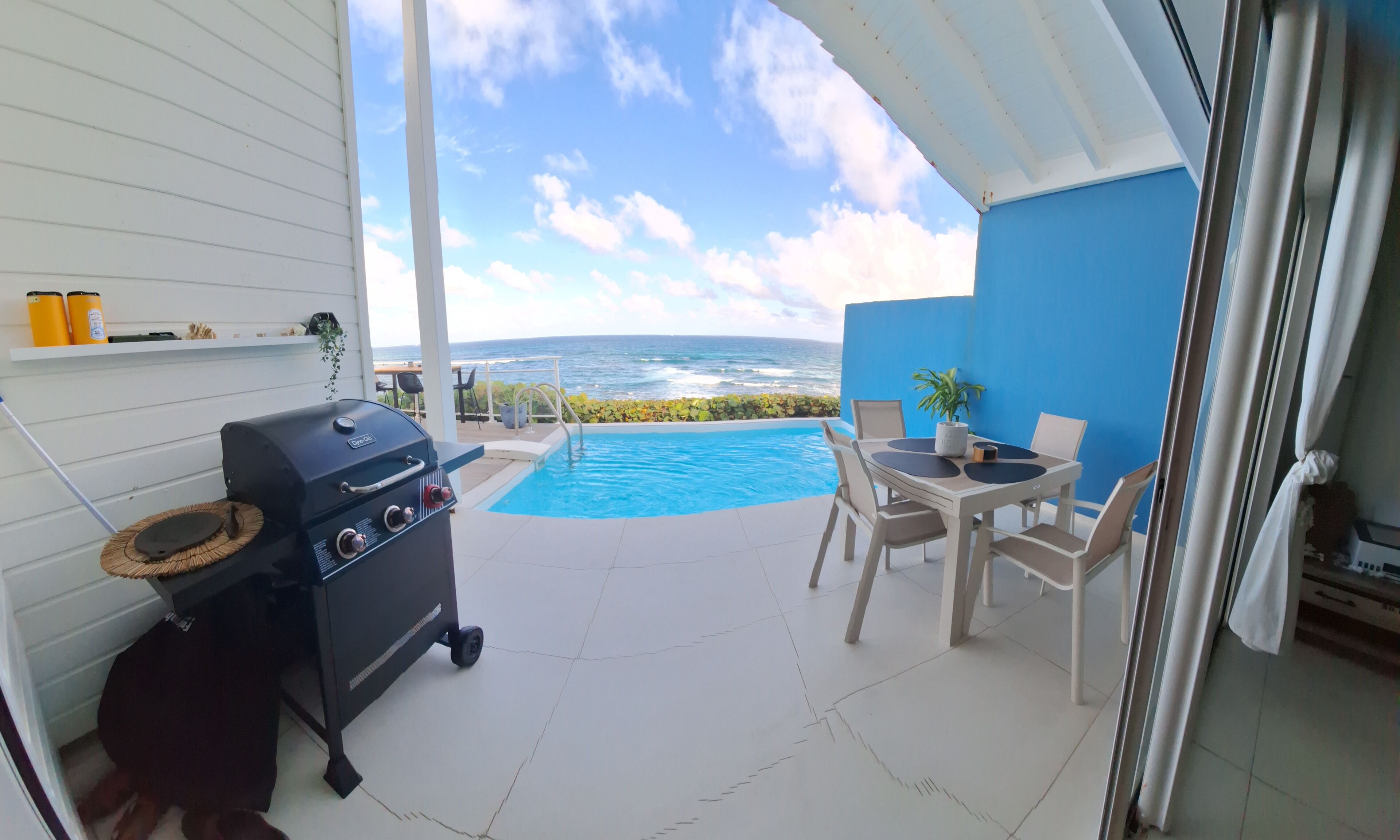 Un balcon avec un barbecue, une piscine et une table avec des chaises.