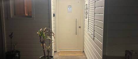 A building entrance with a door marked '1', a small window, and a potted plant.