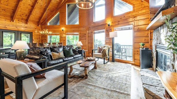 L’intérieur d’une cabane en rondins, avec une cheminée en pierre, un plafond en bois et un sol en pierre.