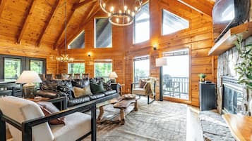 A log cabin interior with a stone fireplace, wooden ceiling, and a stone floor.