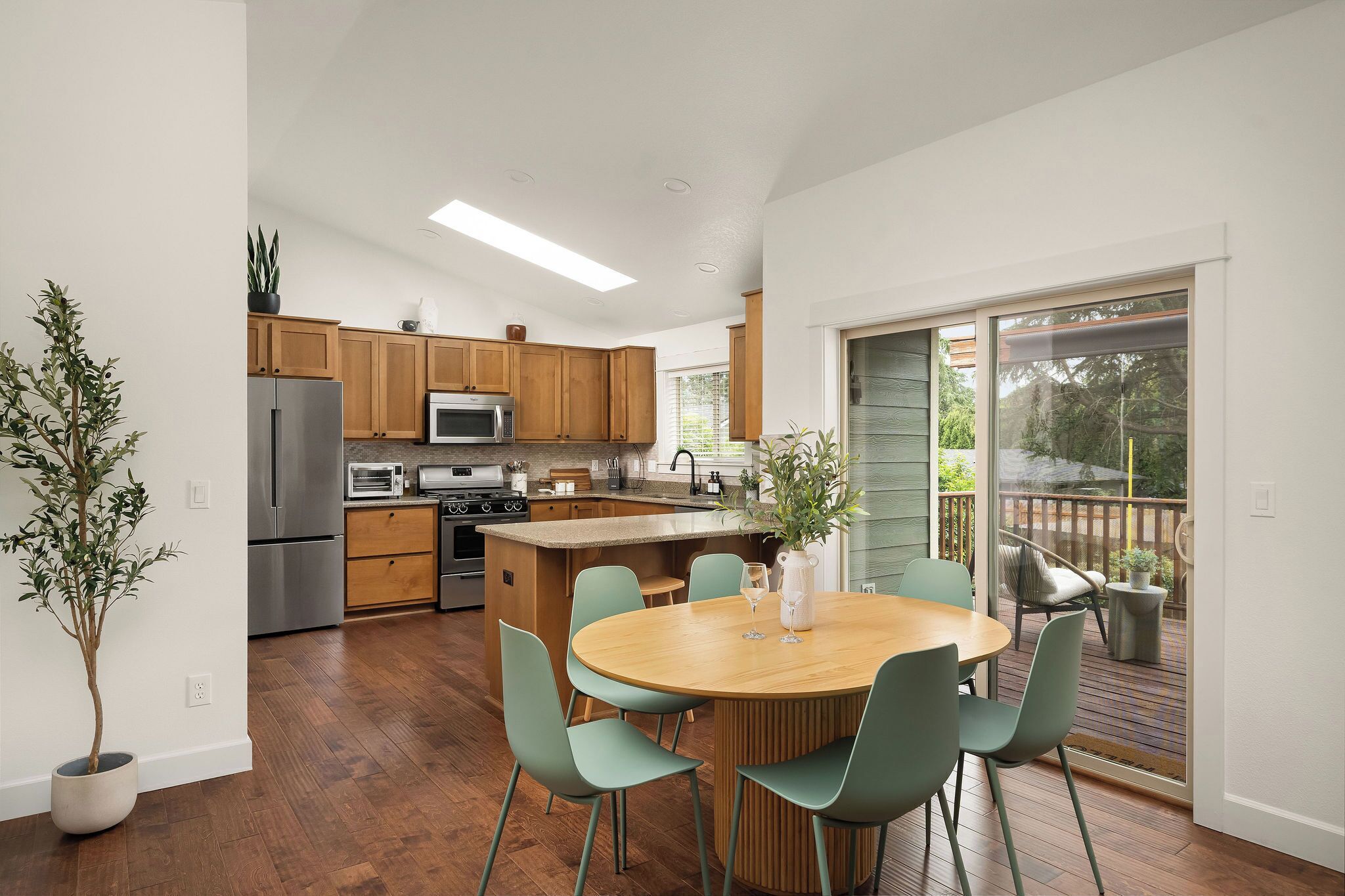 A modern kitchen with wooden cabinets, stainless steel appliances, and a central island with seating.