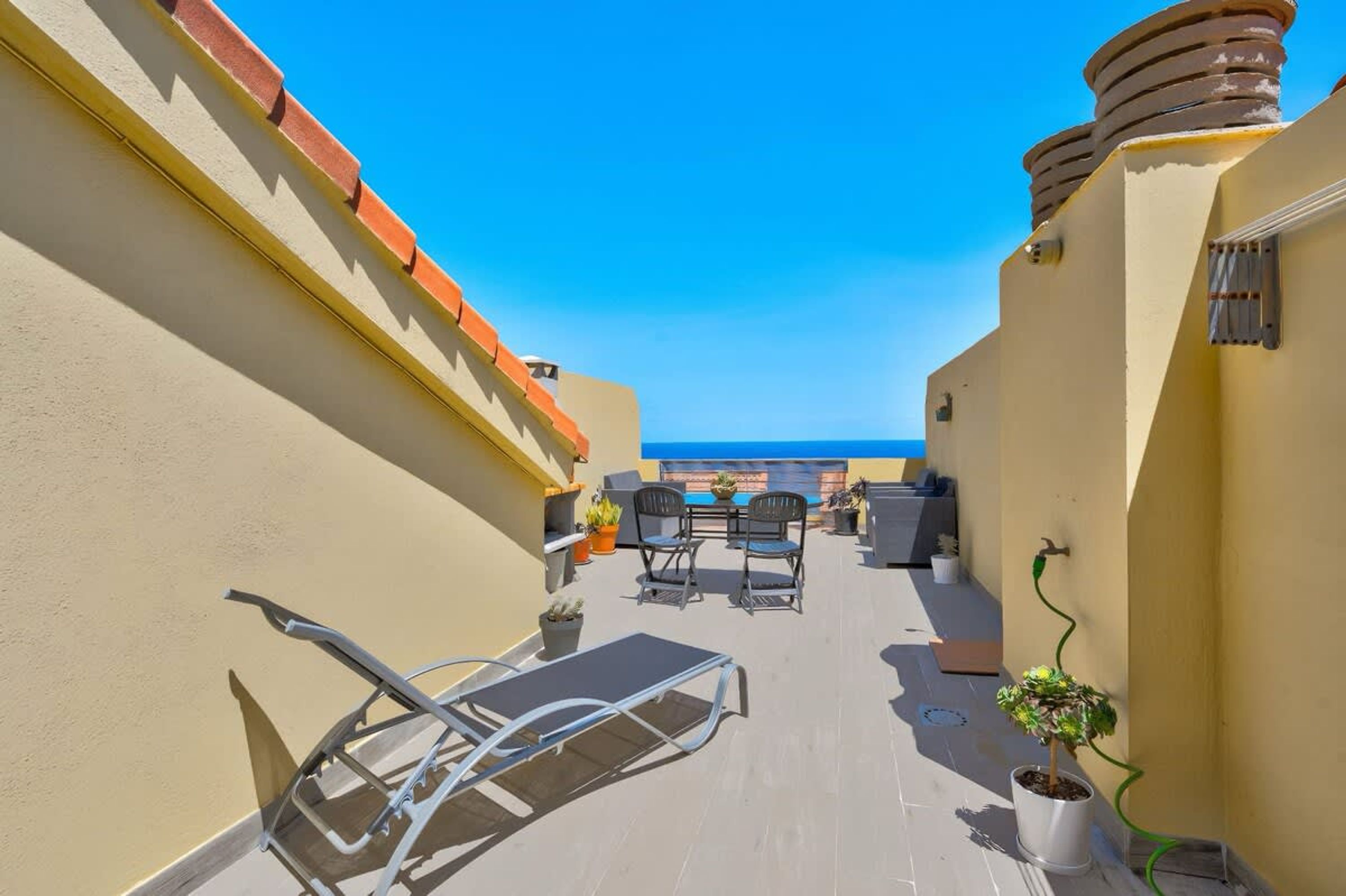 Eine Dachterrasse mit Billardtisch, Stühlen und Topfpflanzen.